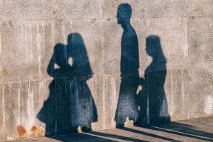 Sombras de tres personas sobre una pared de concreto