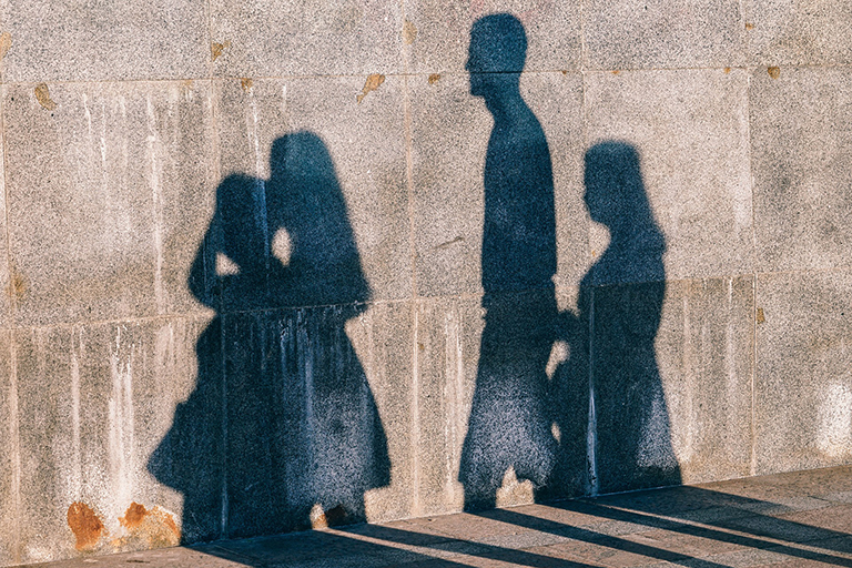 Sombras de tres personas sobre una pared de concreto